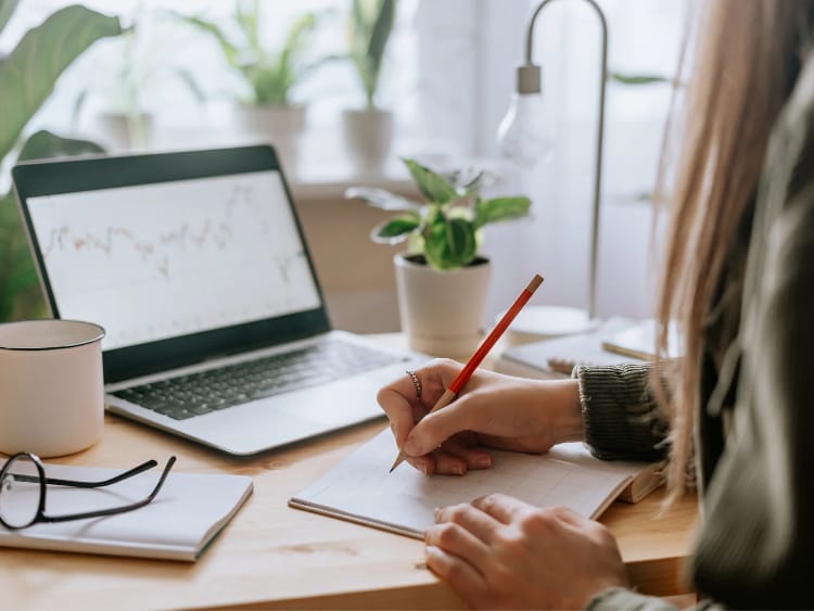 Educação Financeira. Buscar conhecimento é essencial para quem está começando. Mulher estudando finanças em frente a um laptop.