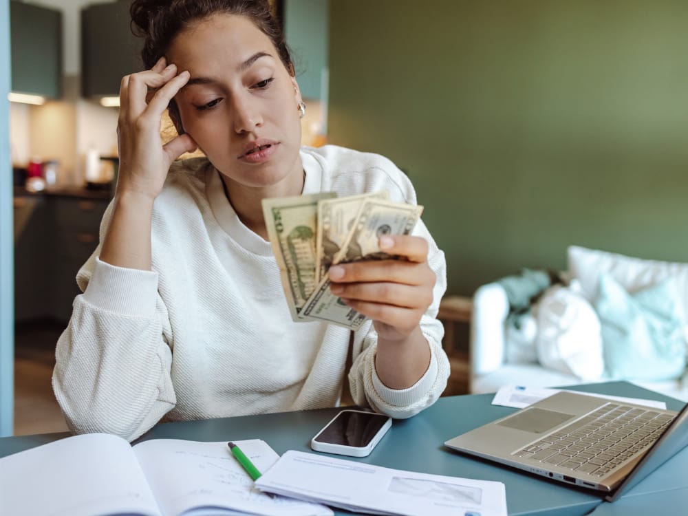 7 Dicas Essenciais de Finanças para Mulheres. As finanças pessoais podem ser um desafio. Imagem de uma mulher com dinheiro nas mãos pensando o que fazer.