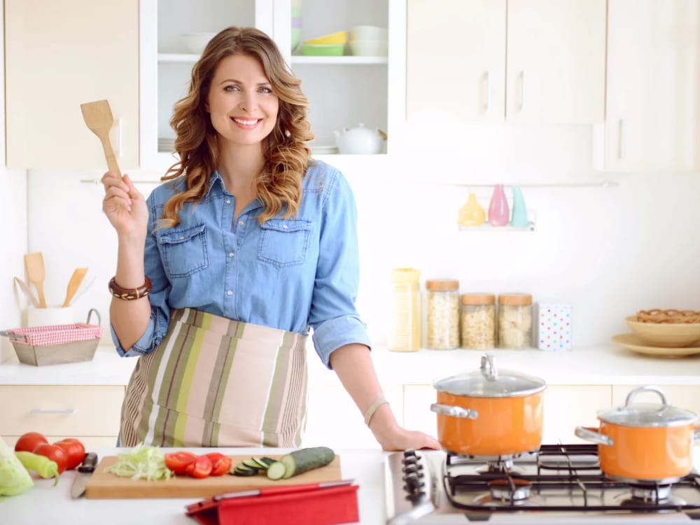 Como empreender na cozinha em 5 passos. imagem ilustrativa de uma chef de sucesso em sua cozinha mostrando seus utensílios