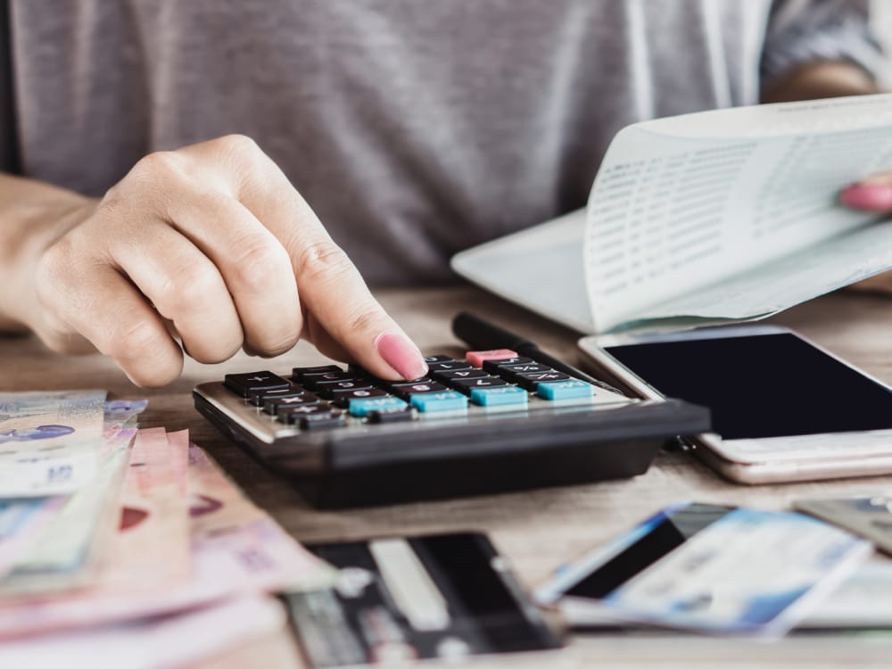 mulher sentada numa mesa fazendo as contas com uma calculadora