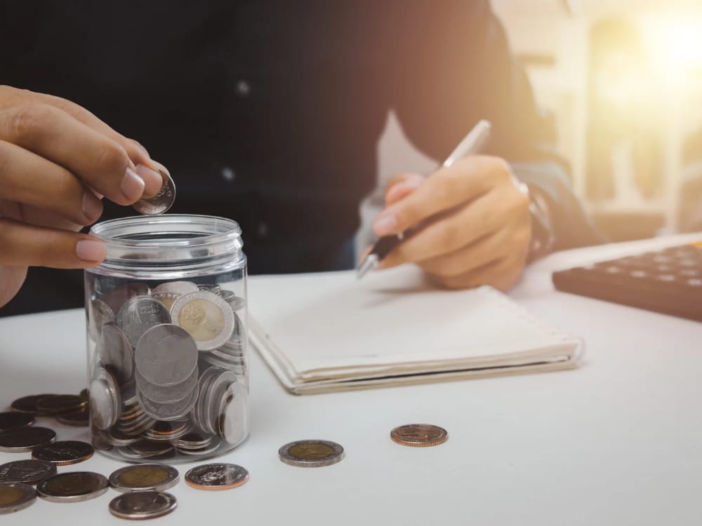 Uma mulher está sentada em uma mesa com um caderno, uma calculadora e um planejador de orçamento. Ela é focada e determinada, cercada de recursos de planejamento financeiro